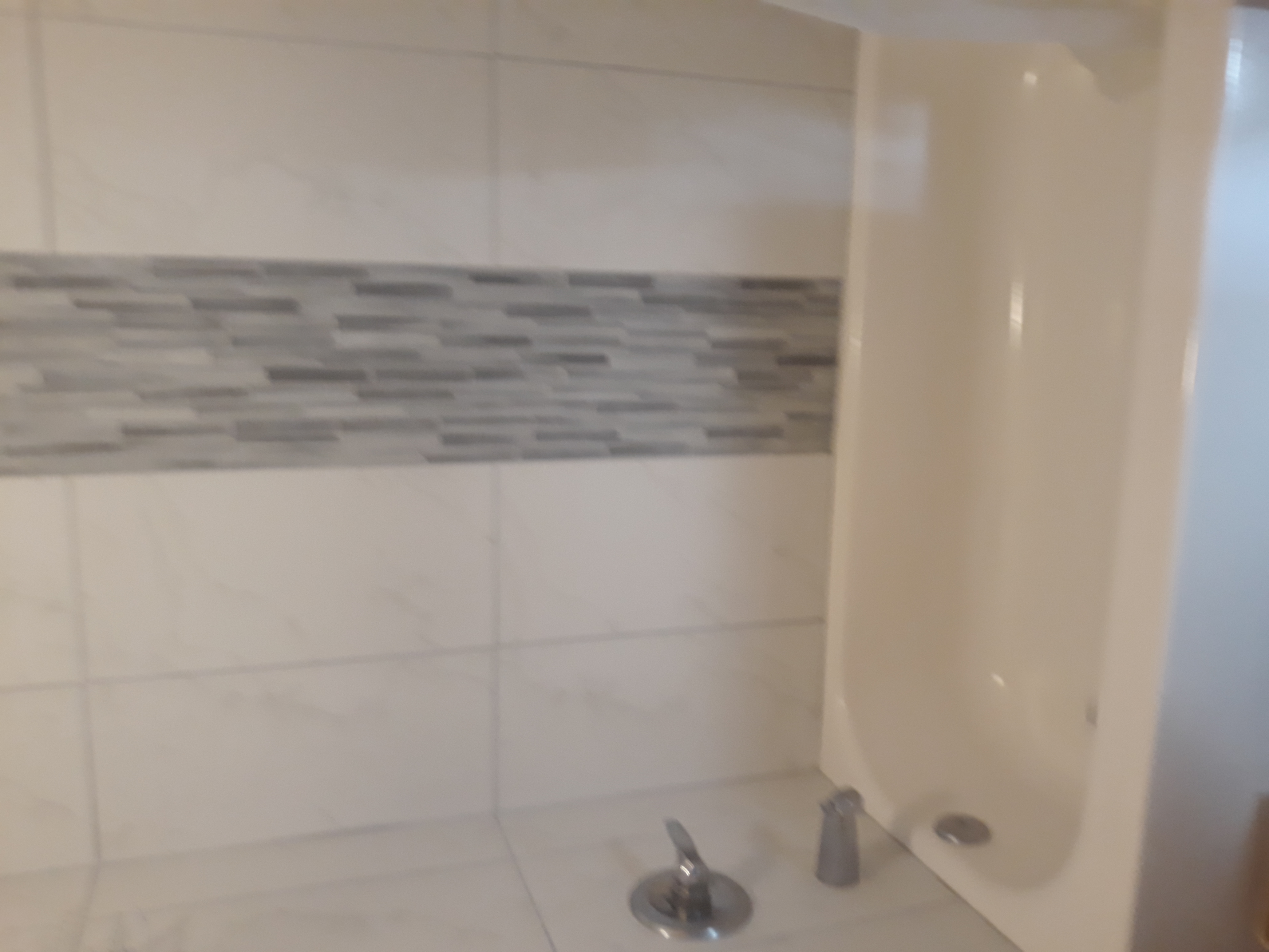 The shower is tastefully tiled.